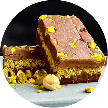 Two slabs of Chocolate and Pistachio Fudge based on Dubai Chocolate. Each bar rests on a grey stone block with a black background